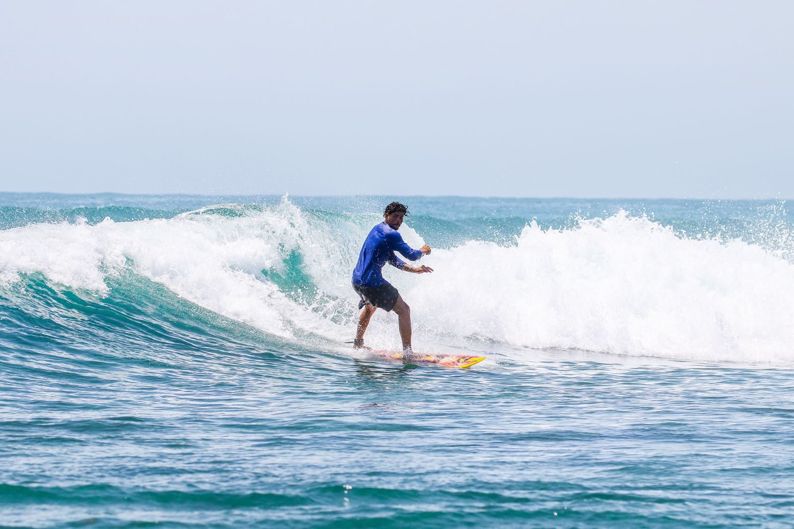 A surfer rides a wave, showcasing skill and balance in a vibrant ocean setting. This image highlights the excitement of surfing.