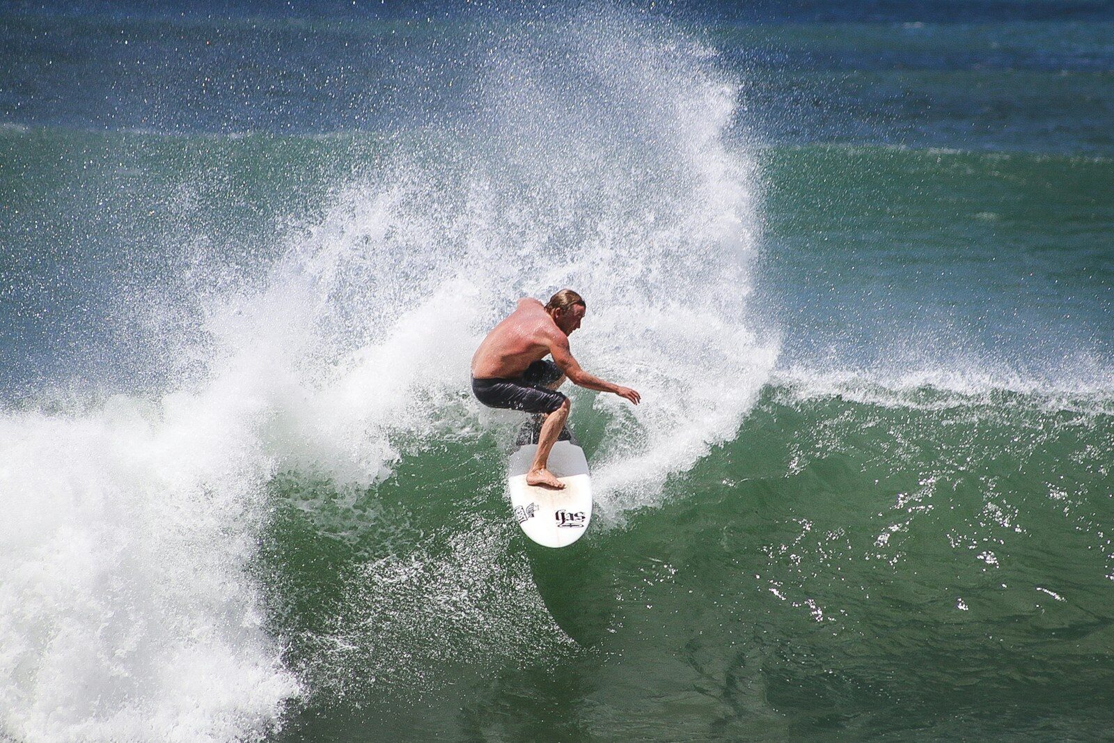 Surfer carving through a wave, showcasing skill and balance in the water. This dynamic scene highlights the thrill of surfing.